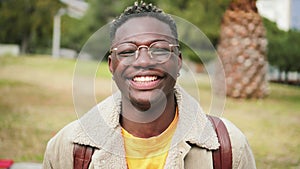 Close up portrait of african american teenage boy looking at camera smiling and laughing at univesity campus. Smart