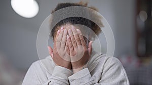 Close-up portrait of African American woman with disgust facial expression closing face with hands. Dissatisfied young