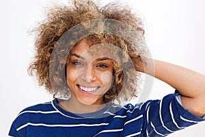 Close up portrait african woman smiling with hand in curly hair against white background