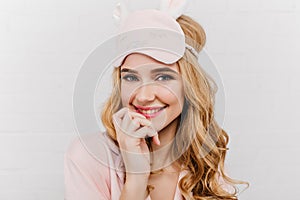 Close-up portrait of amazing blue-eyed young woman in trendy eyemask. Indoor photo of sensual curly white female model