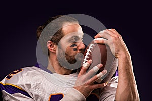 Close up portrait of American Football Player who gently kiss the ball