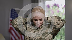 Close-up portrait of anxious military woman with PTSD unzipping camouflage uniform breathing rapidly. Young beautiful
