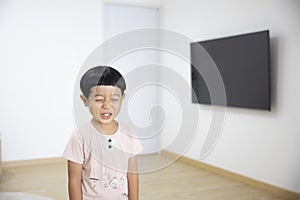Close-up portrait Asian child boy straight black hair wearing a light brown shirt looking at camera of him make funny faces of