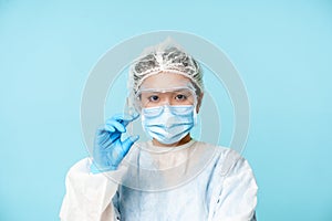 Close up portrait of asian female doctor, nurse in personal protective equipment showing syringe with vaccine