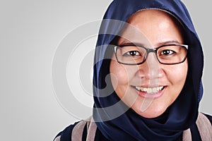 Close up portrait of Asian muslim woman wearing hijab and glasses, smiling at camera