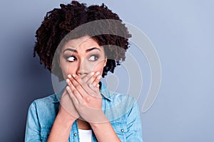 Close up portrait of astonished girl denim clothes hear shocked story arms close mouth look empty space  on gray