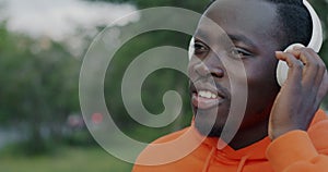 Close-up portrait of attractive African American man wearing headphones listening to music and dancing in city