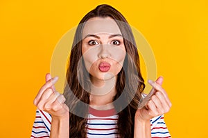 Close-up portrait of attractive amorous girl showing korean love symbol sending air kiss isolated over bright yellow