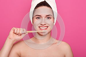 Close up portrait of attractive caucasian smiling woman isolated over pink studio, brushing her teeth in bathroom, doing morning