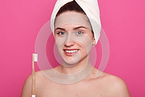 Close up portrait of attractive caucasian smiling woman, looks at camera, holding toothbrush, posing isolated over rosy, lady