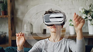 Close-up portrait of attractive curly-haired girl putting on augmented reality glasses and moving head and hands