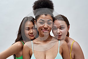 Close up portrait of attractive female friends, multiethnic young women in colorful underwear looking at camera, posing