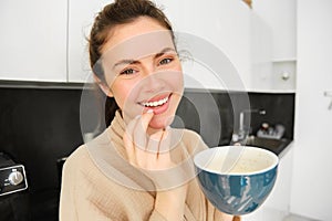 Close up portrait of attractive girl drinking coffee, holding cup with morning cappuccino and smiling, having a mug of