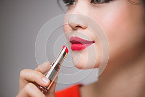 Close up portrait of attractive girl holding red lipstick over g