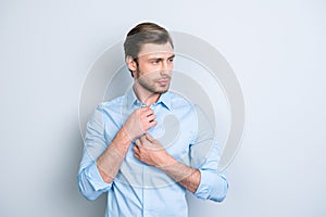 Close up portrait of attractive man correcting buttons on his bl