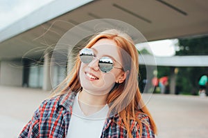 Close up portrait of attractive redhead smiling girl student dressed casual clothes on street in city