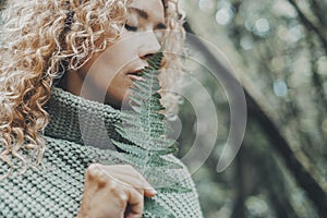 Close up portrait of attractive woman and big tropical leaf near her face. Feeling with nature and people concept lifestyle. Green