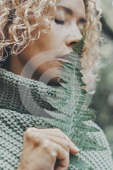 Close up portrait of attractive woman and big tropical leaf near her face. Feeling with nature and people concept lifestyle. Green