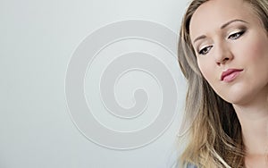 Close-up portrait of attractive young beautiful woman face looking down. Pretty blonde woman with green eyes