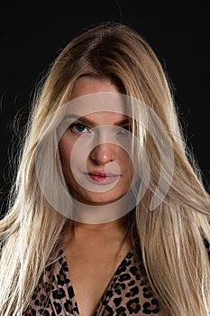 Close-up portrait of an attractive young blonde woman. Long hair. Black background.