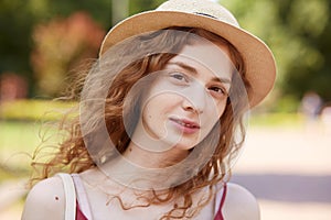 Close up portrait of attractive young lady in straw hat. Foxy haired charming woman with brown eyes looking at camera with gentle