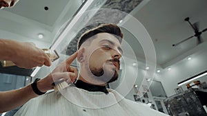 Close-up portrait of attractive young man getting trendy haircut.