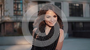 Close-up portrait of an attractive young woman in an autumn coat against a background of urban architecture