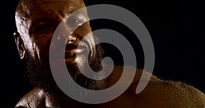 Close-up portrait of a bearded bald brutal male bodybuilder with a bare torso, he is in the Studio on a black background