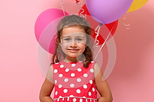 Close-up portrait of beautiful 4 years baby girl, smiling looking at camera, isolated over pink background, copy space.