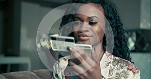 Close up portrait of a beautiful African American female with curly hair entering her credit card details on her