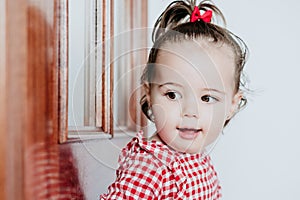 Close up portrait of beautiful baby girl at home looking by window door. One year old girl. Lifestyles indoor