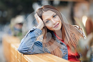 Close up portrait of a beautiful blonde girl Hand Lean Face sitting outdoor in cozy cafe in town. Pretty young model looking at ca photo