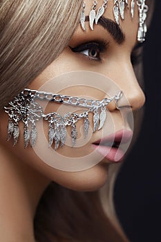 Close-up Portrait of a beautiful blonde girl. Jewelry accessories on the face of model. Beauty and style concept.