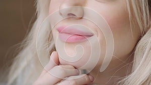 Close-up portrait of beautiful blonde woman lying on the bed with gray aluminum laptop. Girl smiles, good mood. Blogging