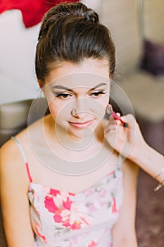 Close-up portrait of the beautiful bride. The artist is doing the make-up.