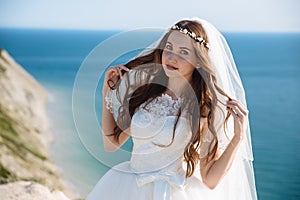 Close up portrait of beautiful bride with veil, wedding makeup, hairstyle and jewelry wreath on long curly hair.