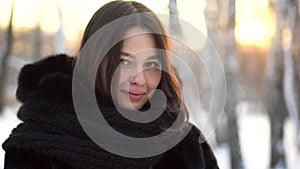 Close up portrait of beautiful brunette girl in black fur coat and big, knitted scarf outdoor in winter frost forest