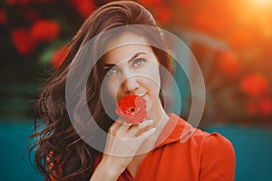 Close-up portrait of beautiful brunette woman with red rose in her lips. Toned image