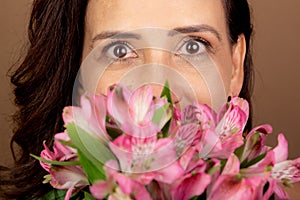 Close-up portrait of beautiful Caucasian woman holding bouquet of flowers close to her face. Passionate, happy person