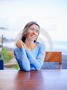 Close up portrait of beautiful Caucasian woman. Smiling woman wearing blue dress and sitting in the beach bar. Travel lifestyle.
