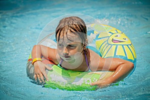 Close up portrait of beautiful child girl in swimming pool relax swim on inflatable ring. Summer holiday, vacation and happy