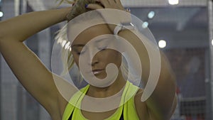 Close-up portrait of beautiful confident sportswoman making ponytail. Charming Caucasian blond woman preparing for