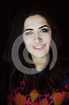 Close-up portrait of beautiful elegant brunette with long hair. In the eyes of the reflection of the lamp. Studio, dark