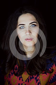 Close-up portrait of beautiful elegant brunette with long hair. In the eyes of the reflection of the lamp. Studio, dark