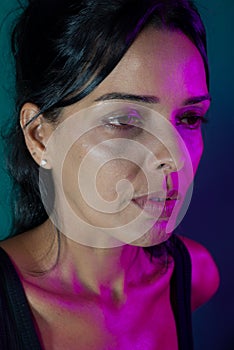 Close-up portrait of beautiful fashion model wearing looking to the side. Pink color on one side of the face