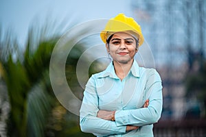 Close up portrait of beautiful female engineer wearing a protective helmet and looking at camera