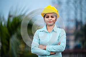 Close up portrait of beautiful female engineer wearing a protective helmet and looking at camera