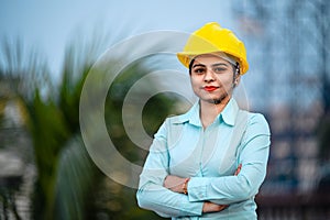Close up portrait of beautiful female engineer wearing a protective helmet and looking at camera