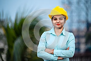 Close up portrait of beautiful female engineer wearing a protective helmet and looking at camera