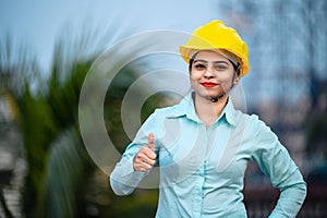 Close up portrait of beautiful female engineer wearing a protective helmet and looking at camera